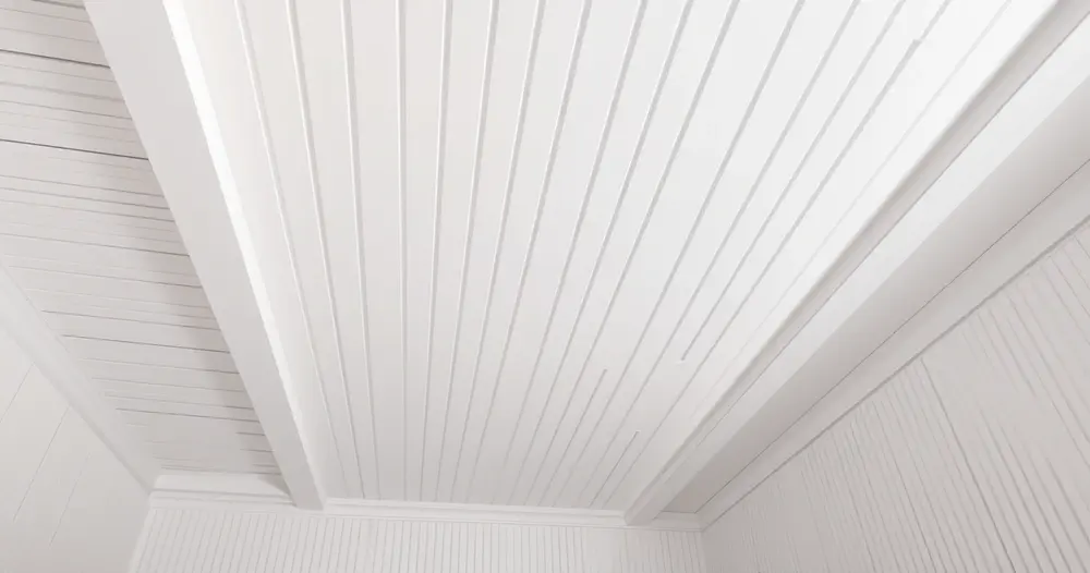 Teto com réguas brancas de forro de PVC instaladas e acabamento em perfil nas bordas